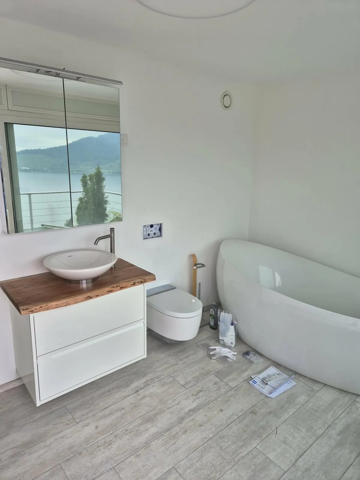 Badumbau mit freistehender Badewanne, Aufsatzwaschbecken auf Holzplatte und wandhängendem WC